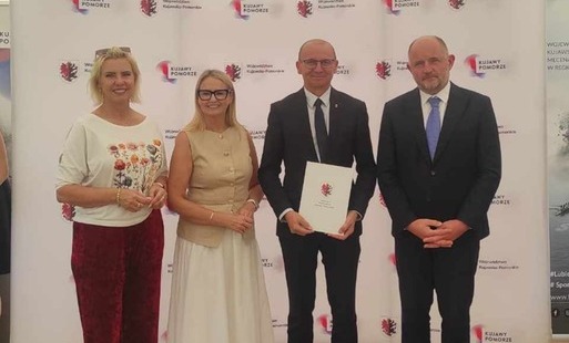 Dwie kobiety i dwóch mężczyzn na tle ścianki z potwierdzeniem zawarcia umowy.